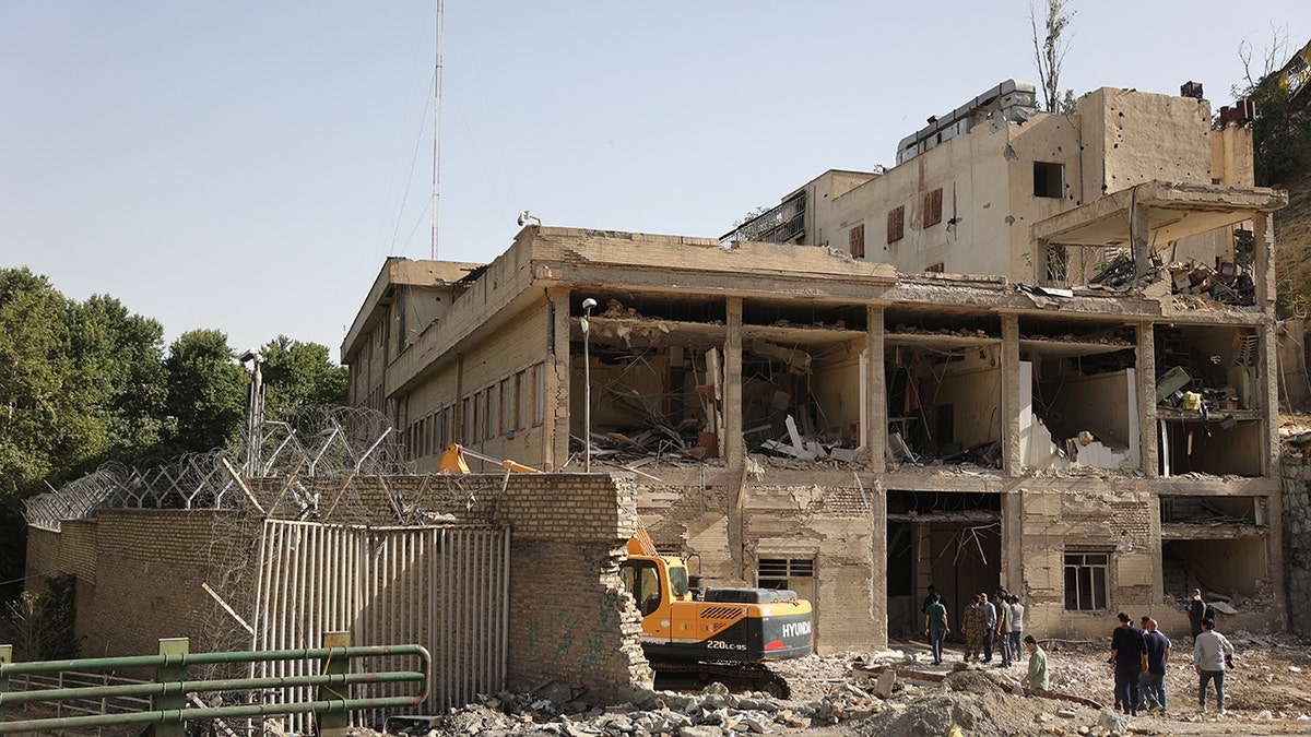 people standing outside destroyed Evin prison