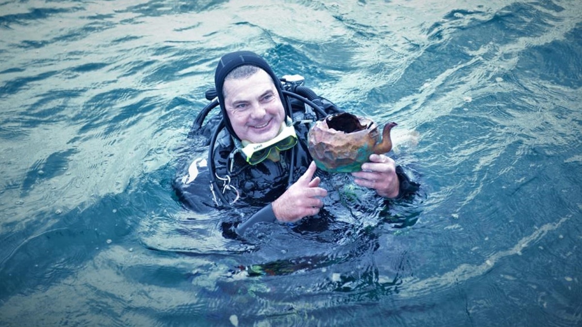 Diver smiling while holding tea kettle