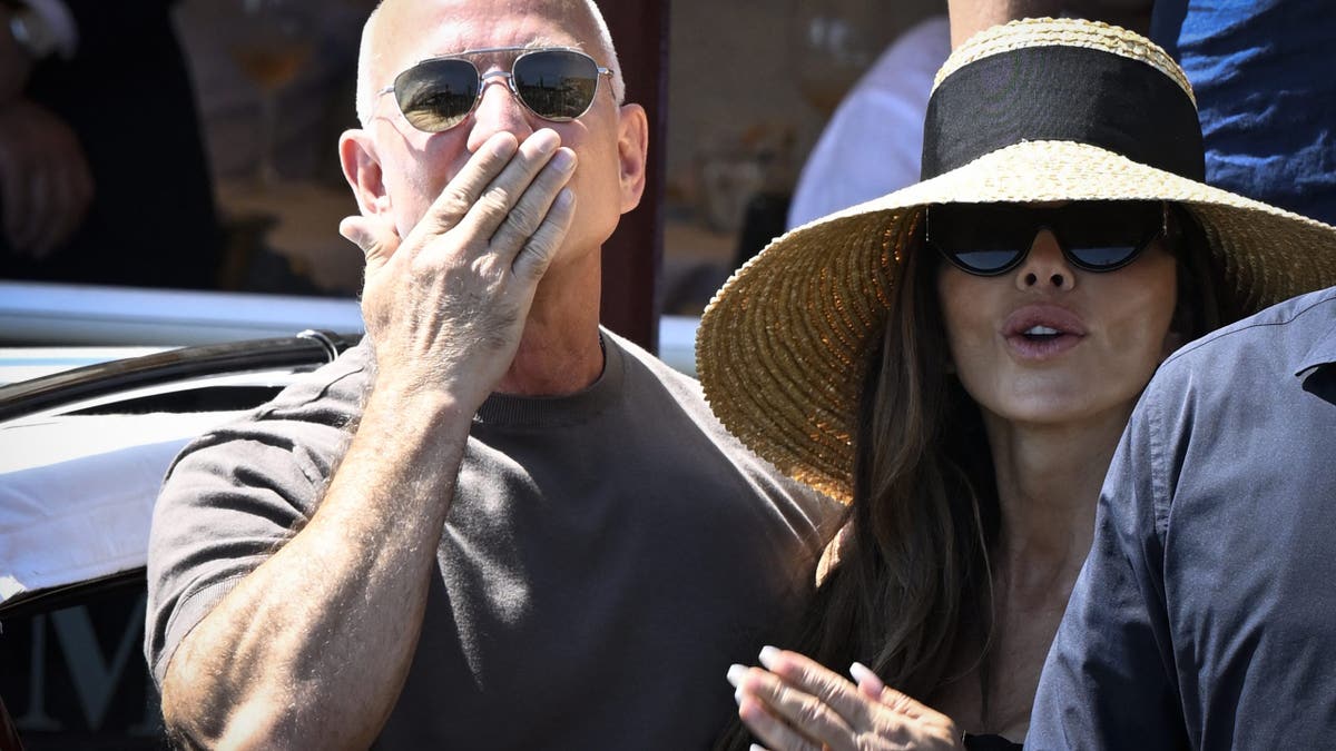 Jeff Bezos blows a kiss to the camera as he stands beside Lauren Sanchez