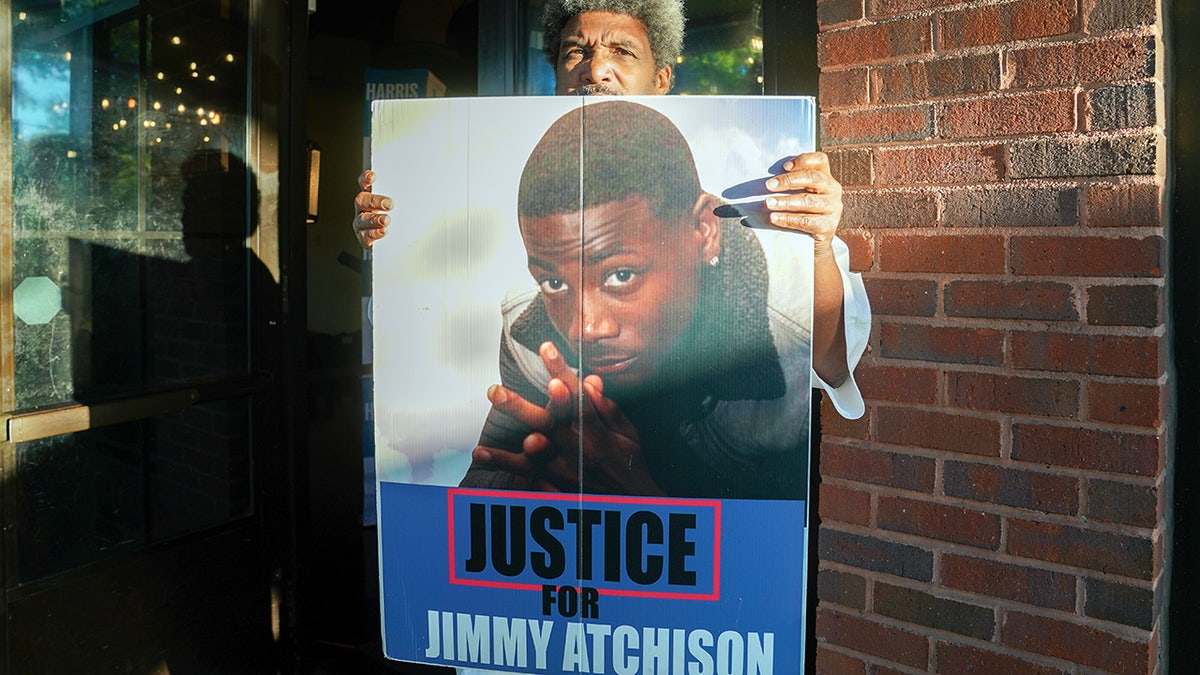 Jimmy Hill holds sign showing image of his late son Jimmy Atchison