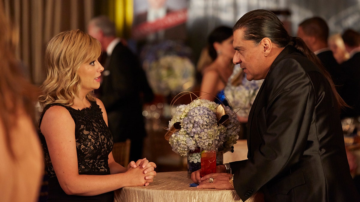Jonathan Joss wears black suit next to Amy Poehler in a black dress