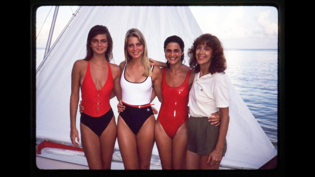 Jule Campbell smiling with a group of models in swimsuits during a shoot.