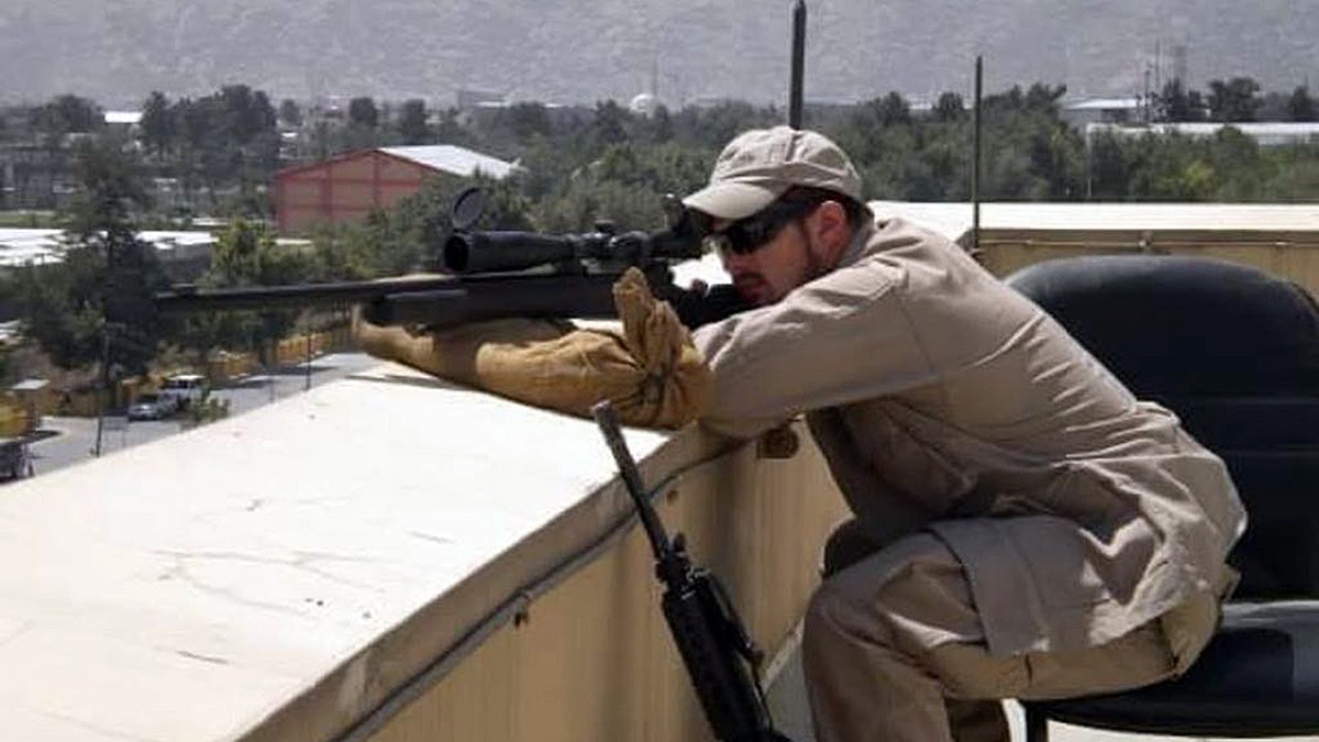 Justin Governale holds a firearm connected a rooftop