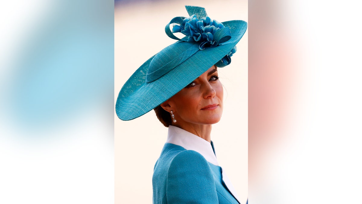 A close-up of Kate Middleton in a blue and white suit with a matching hat.