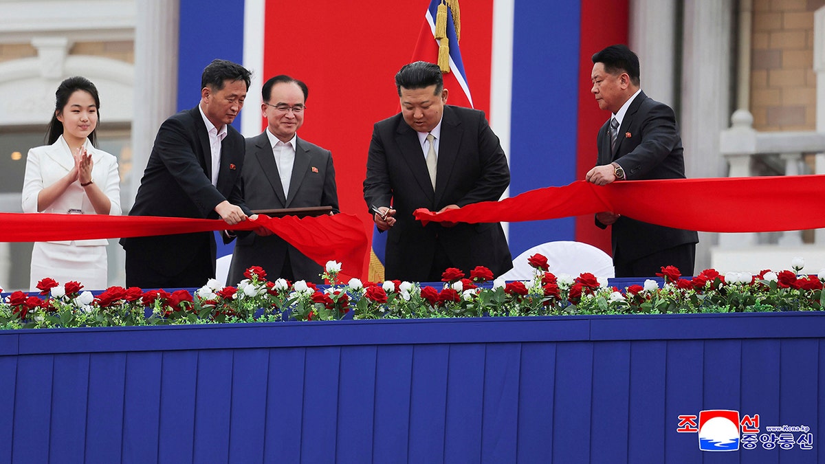 North Korean leader Kim Jong Un wearing dark suit cuts red ceremonial ribbon