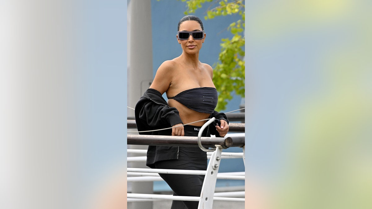 Kim Kardashian wearing a risque black crop top with a black skirt and a black jacket