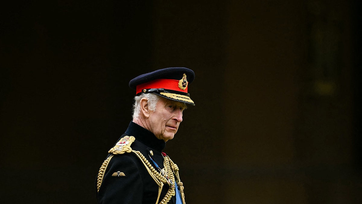 King Charles wearing a military suit looking stern.