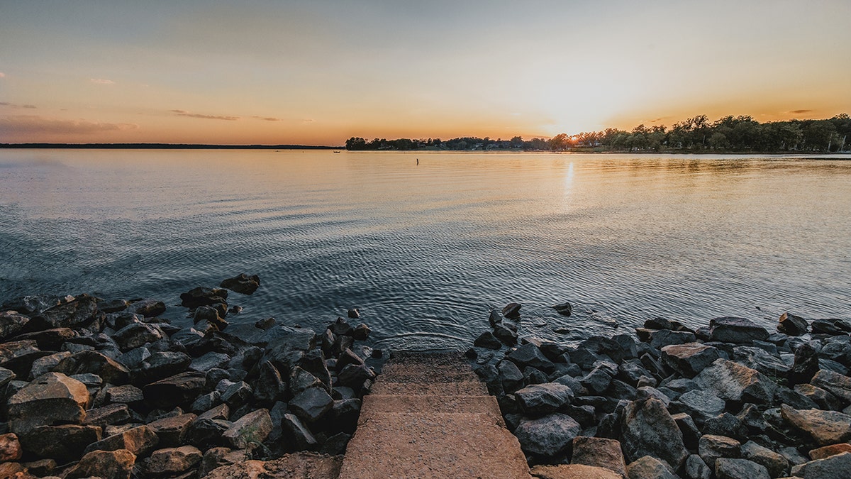 concrete steps lead into lake murray while sun sets over water