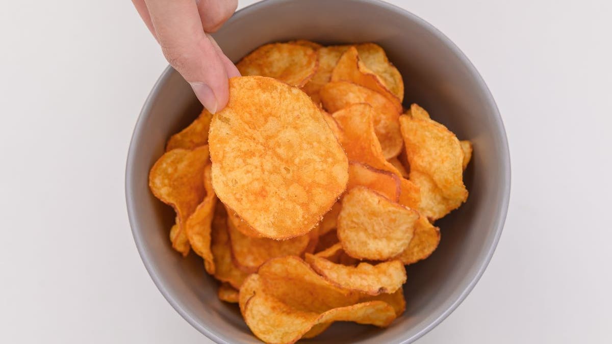 Hand lifting flavored chip from bowl