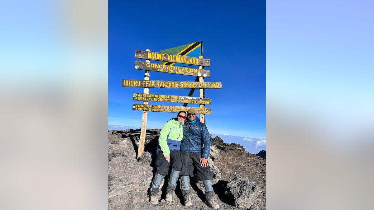 Lindsay Gutierrez on a mountaintop next to a sign.