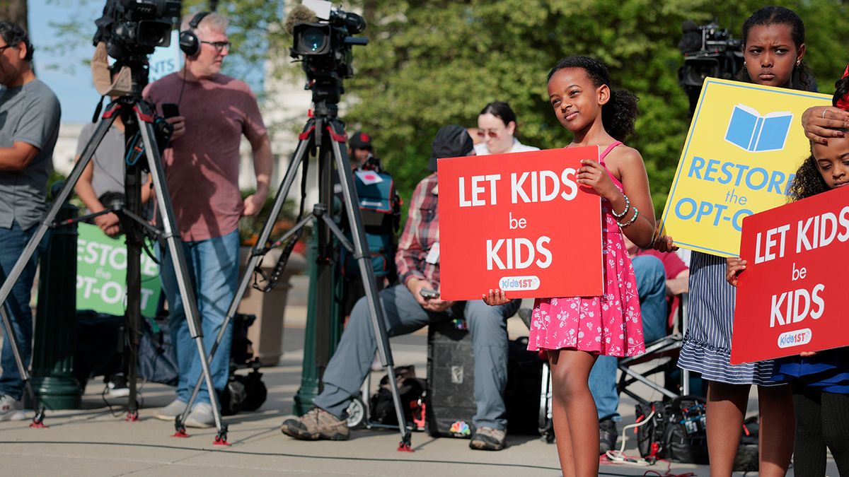 Girl holding 'let kids be kids' sign