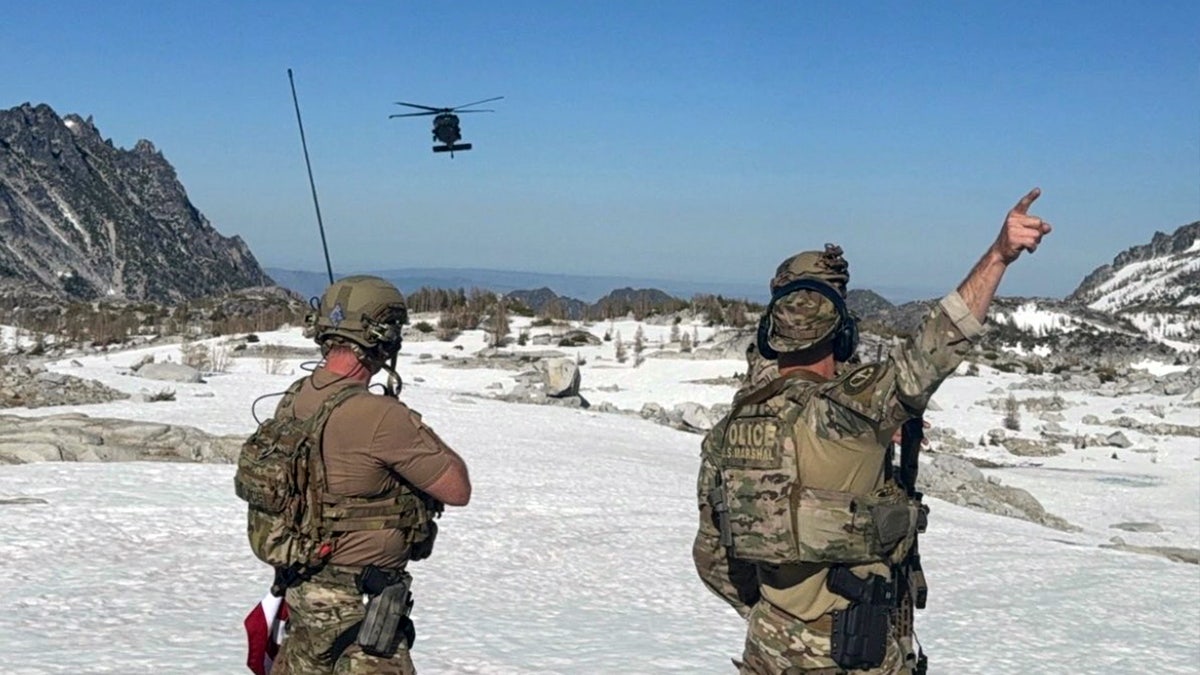 U.S. Marshals members look towards an incoming helicopter
