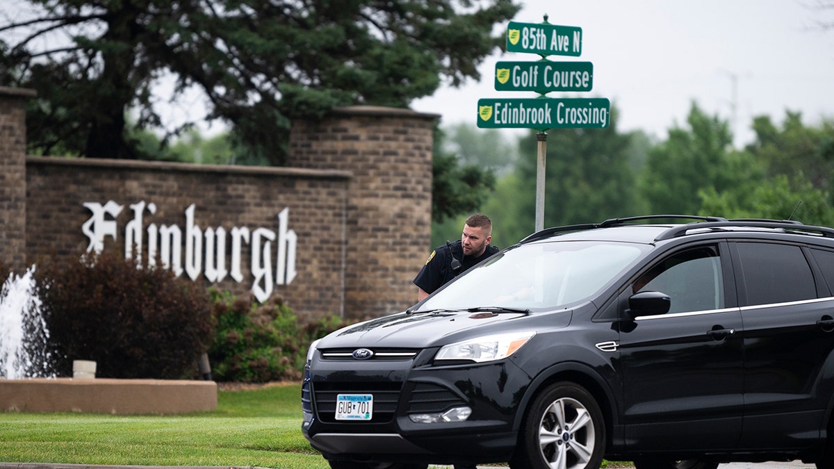 A police officer standing next to a car in front of a street sign