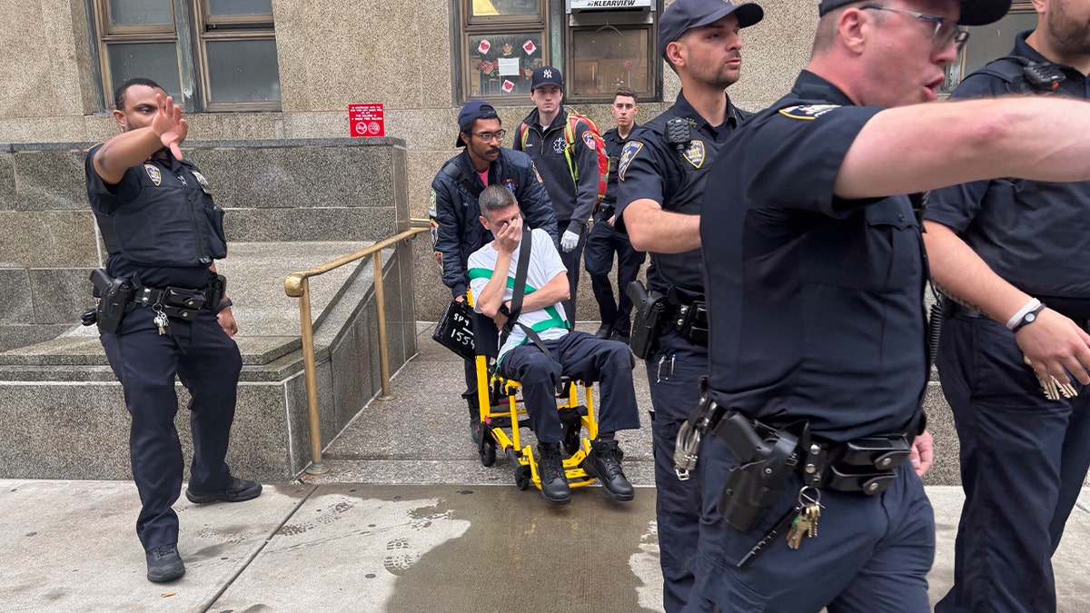 officers escort a man in a gurney outside a New York county courthouse