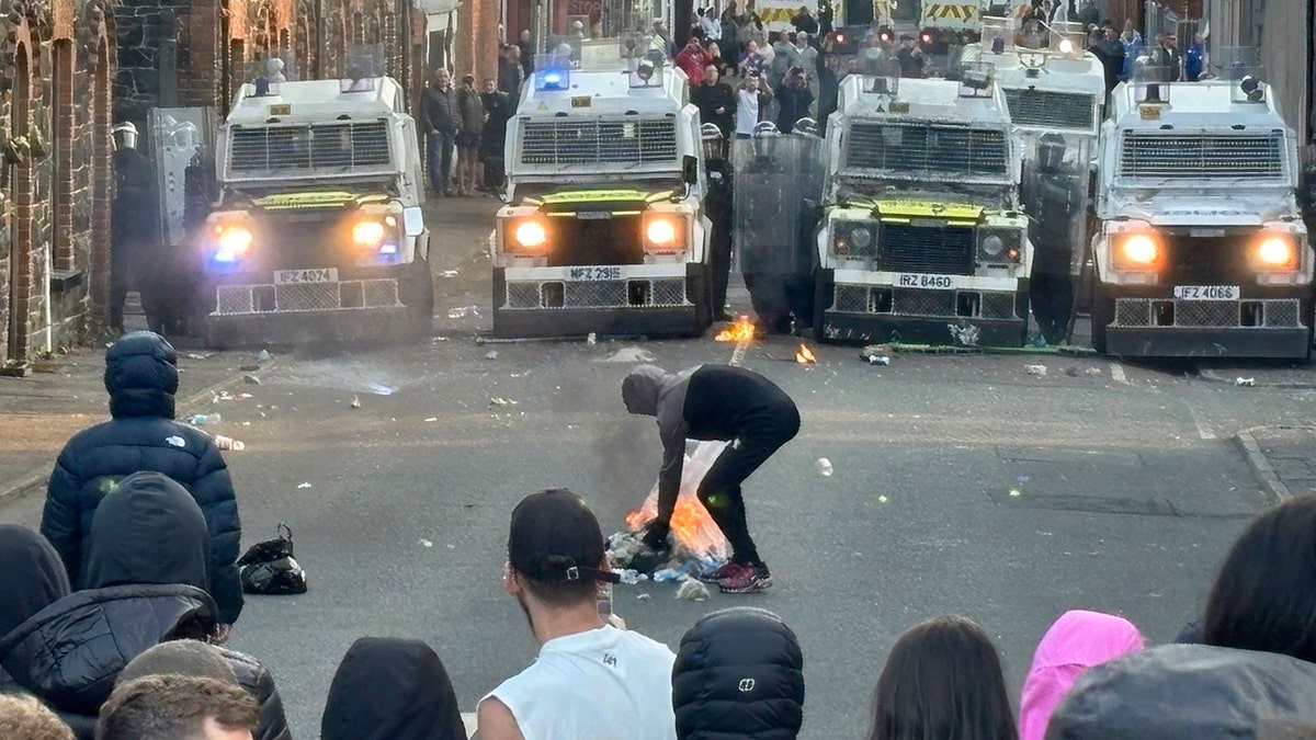 Riot vans in front of a group of protesters