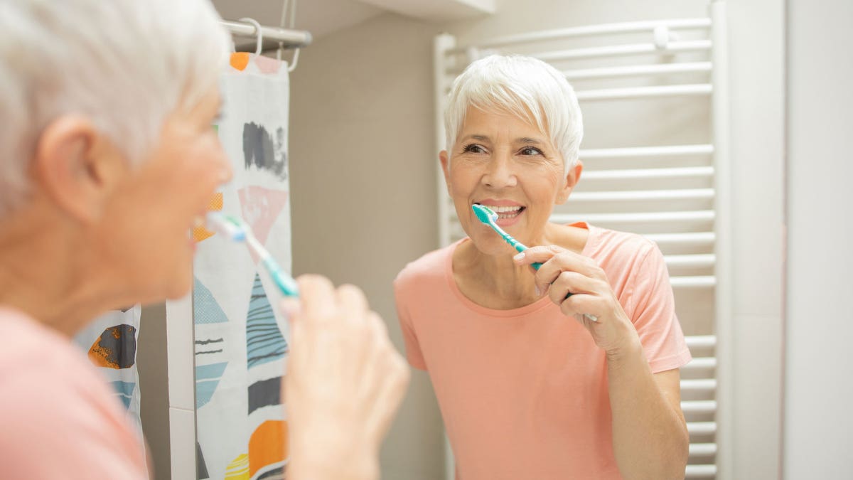 The older woman brushes her teeth