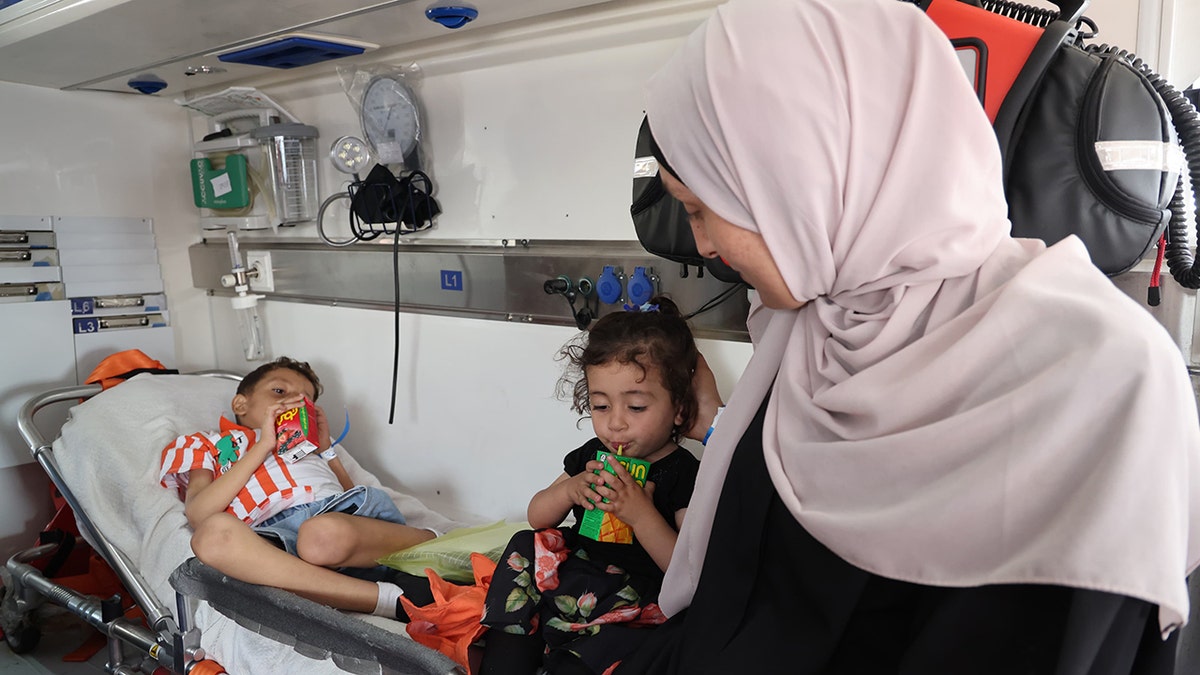 Palestinian children sip juice boxes inside an ambulance provided by the Jordan Armed Forces.