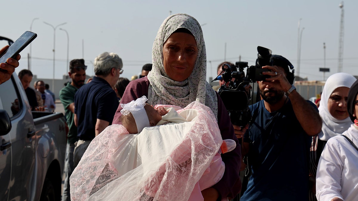 A Palestinian woman carries a baby ahead of evacuation from the Gaza Strip via the Jordan Medical Corridor.