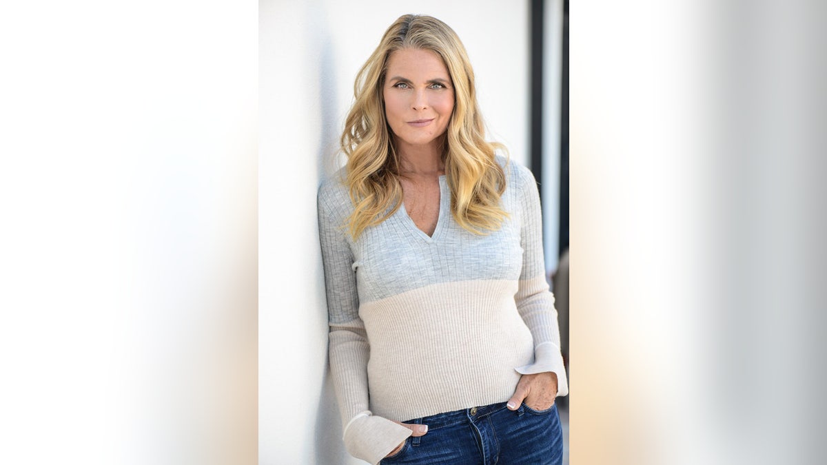 Kim Alexis wearing a grey and beige sweater and jeans.