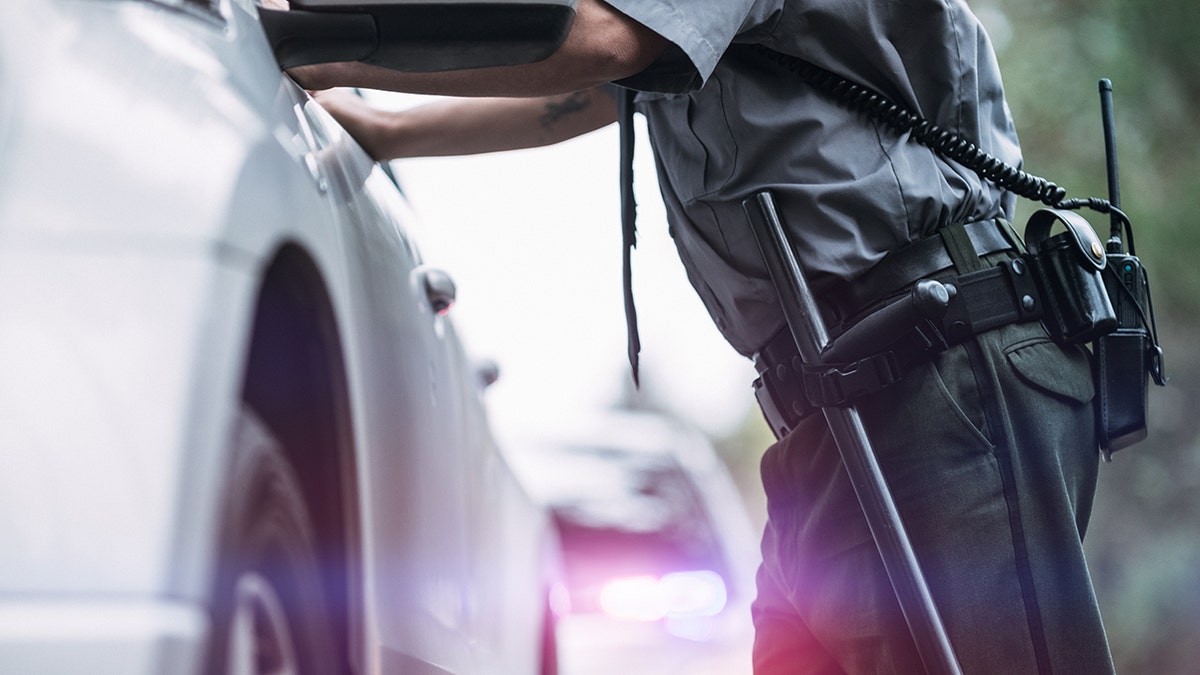 Petugas polisi berdiri di luar kendaraan pengemudi