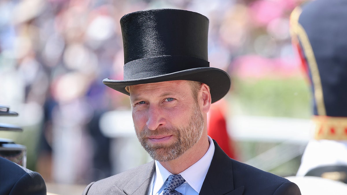 Prince William successful a grey suit and achromatic apical chapeau sitting connected a royal carriage.