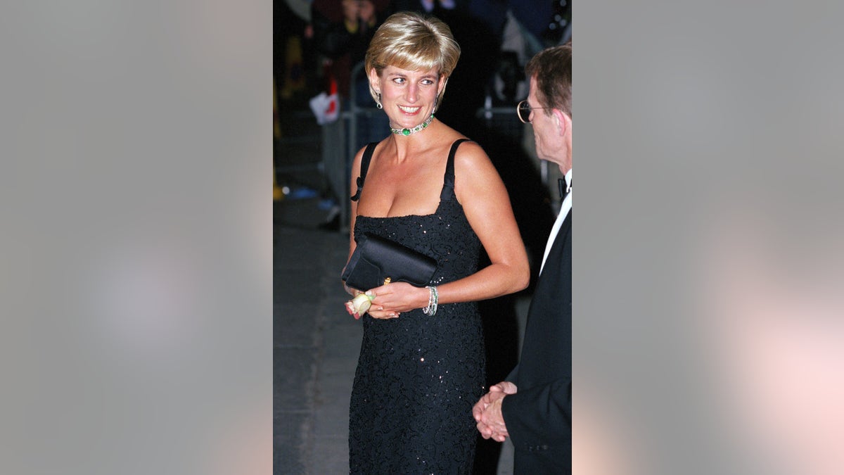 Princess Diana wearing a low-cut strappy black dress with a diamond and emerald choker.