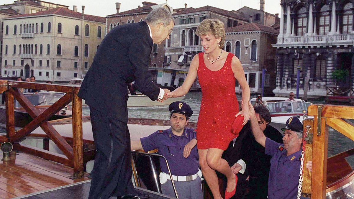Princess Diana wearing a red dress by Jacques Azagury being helped out of a boat in Venice.