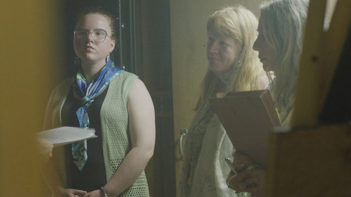 Asa Ellerup and her daughter Victoria standing next to each other inside their dark home and looking serious.