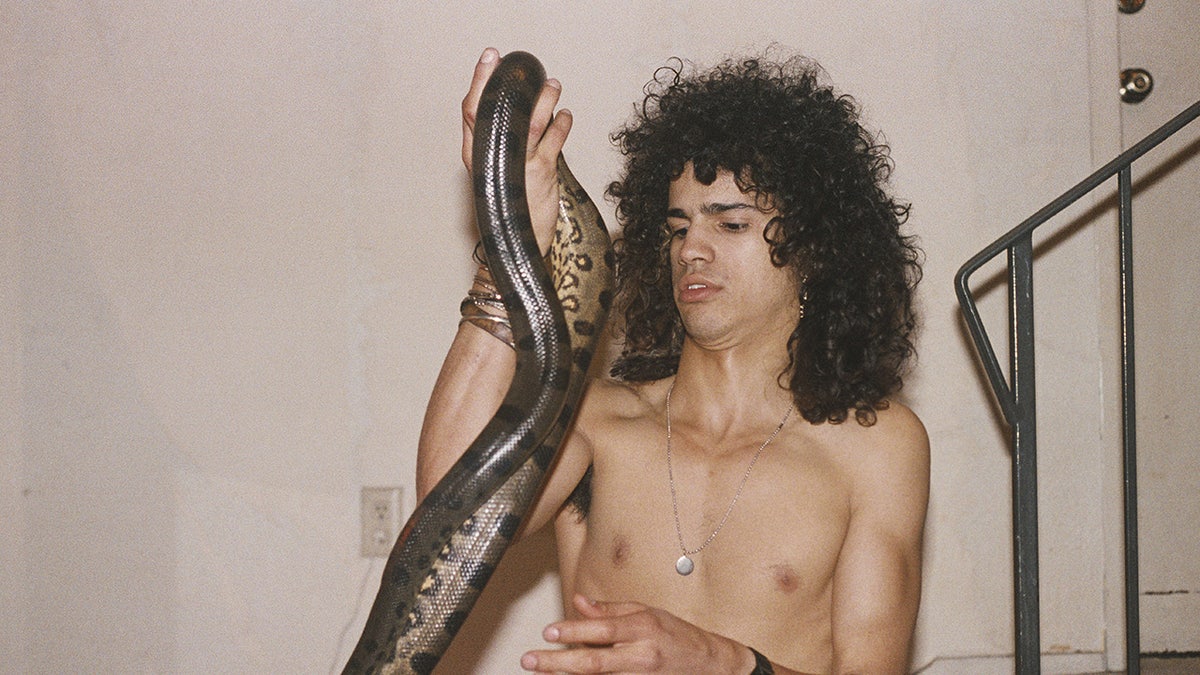 Slash holding up a snake shirtless.