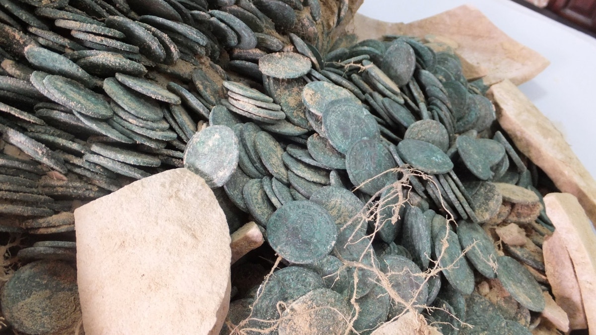 Close-up of broken amphora with coins