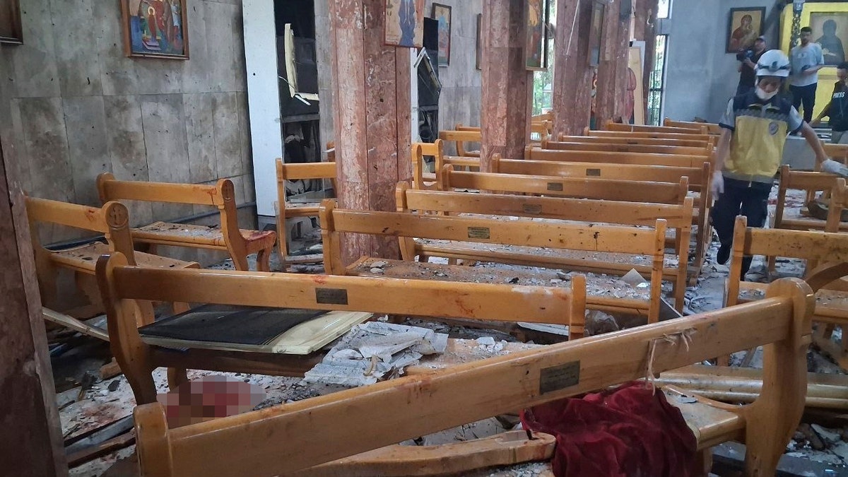 A Civil Defence worker inspects damage inside the Mar Elias church in Dweil'a on June 22, 2025.
