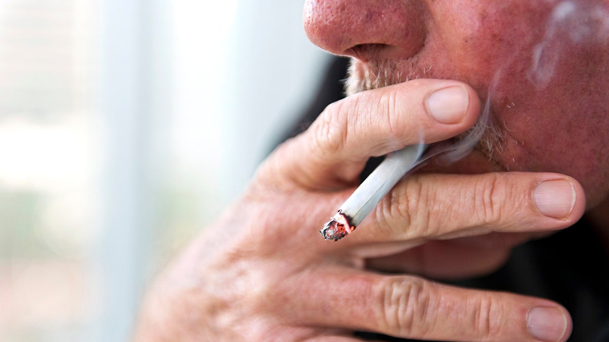Senior Caucasian man approached his fingers when he smoked a cigarette