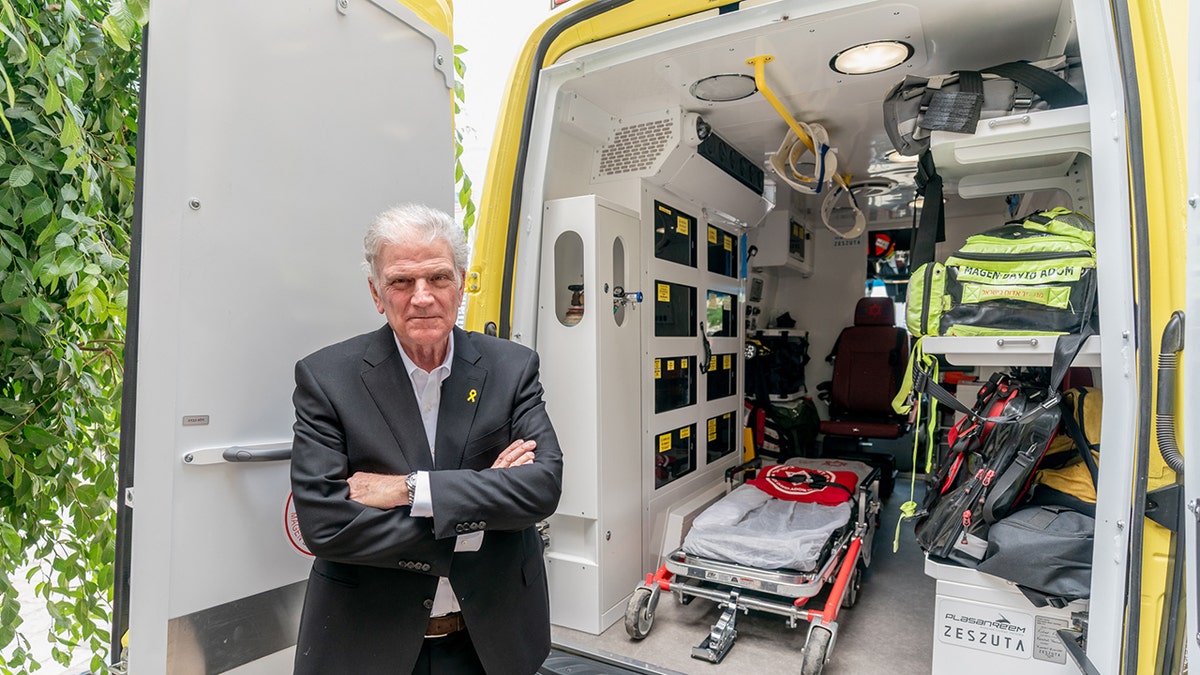 Franklin Graham stands beside an open armored ambulance with ICU equipment visible inside