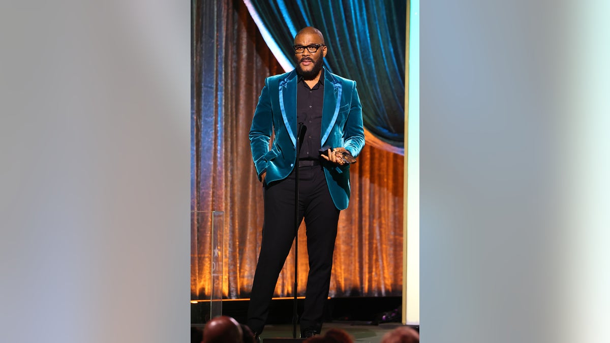 Tyler Perry wears a bright velvety velvety coat and a dark suit that talks on the stage.