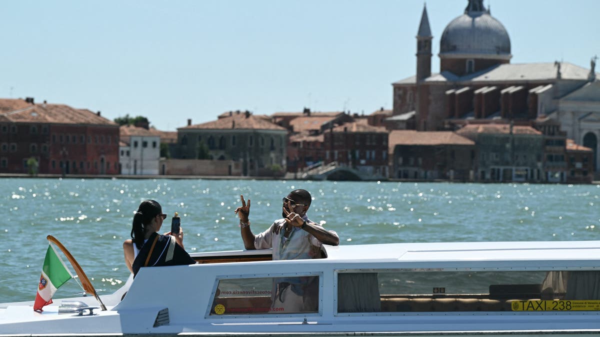 Usher and his wife taking photos on a water taxi in Venice