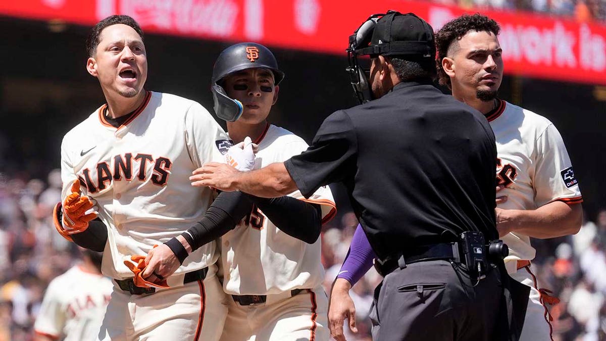 Wilmer Flores is restrained by teammates