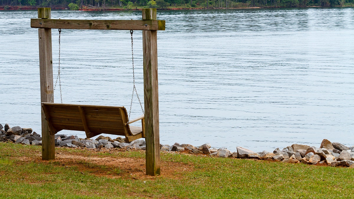 wooden swing next to lake murray on overcast day