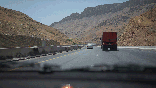 cars drive on highway through arid mountains