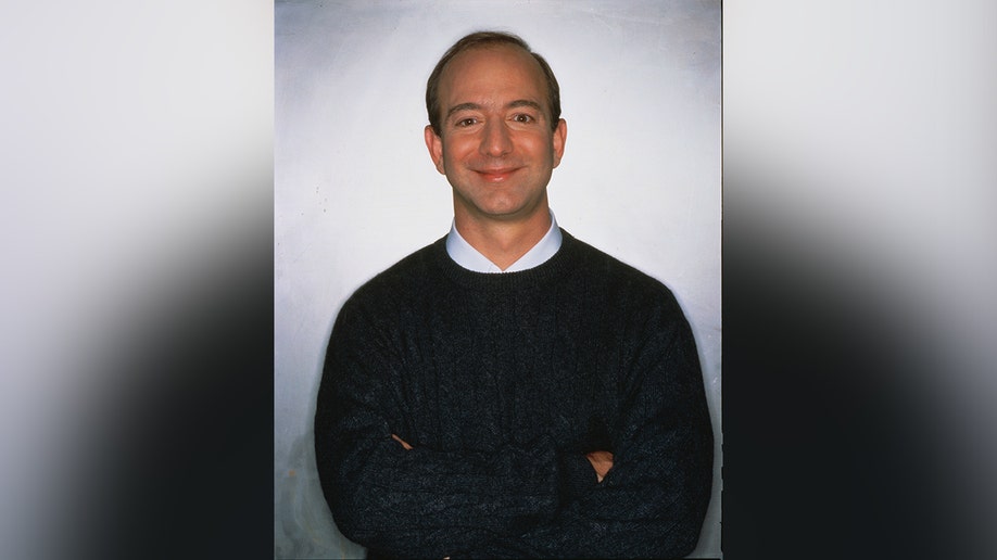 Jeff Bezos posing for a photo in front of a white wall.