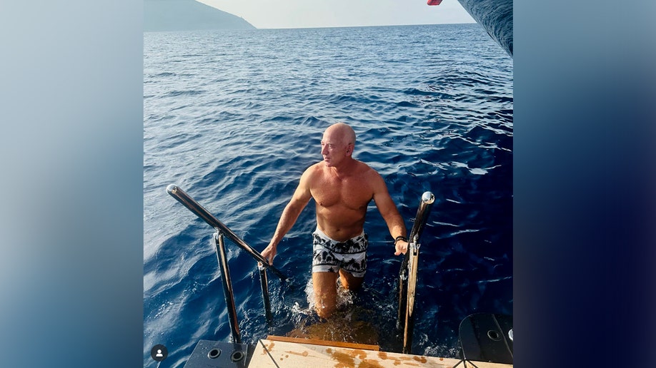 Jeff Bezos getting out of the water and climbing onto the boat.