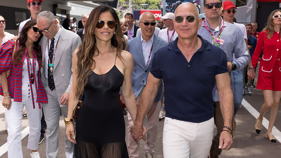 Jeff Bezos and Lauren Sanchez holding hands while being photographed.