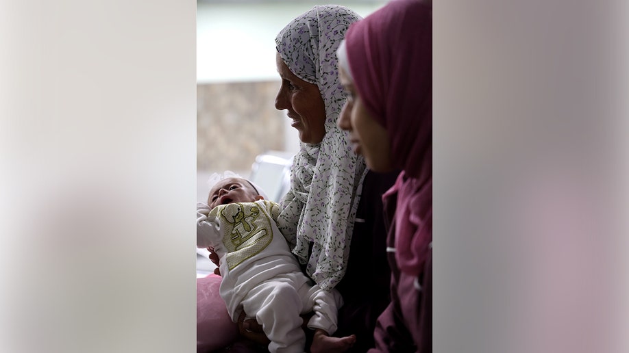 A Palestinian woman holds a baby as they wait to be evacuated from the Gaza Strip by the Jordan Armed Forces.