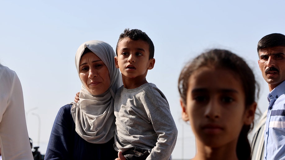 A Palestinian mother carries her son before they are evacuated from Gaza by the Jordanian army.