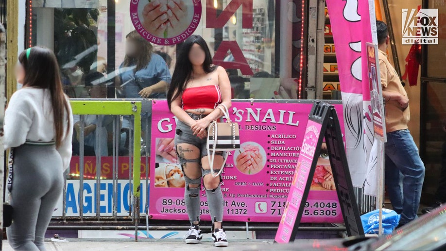 An alleged prostitute stands on a Queens sidewalk on Roosevelt Avenue.