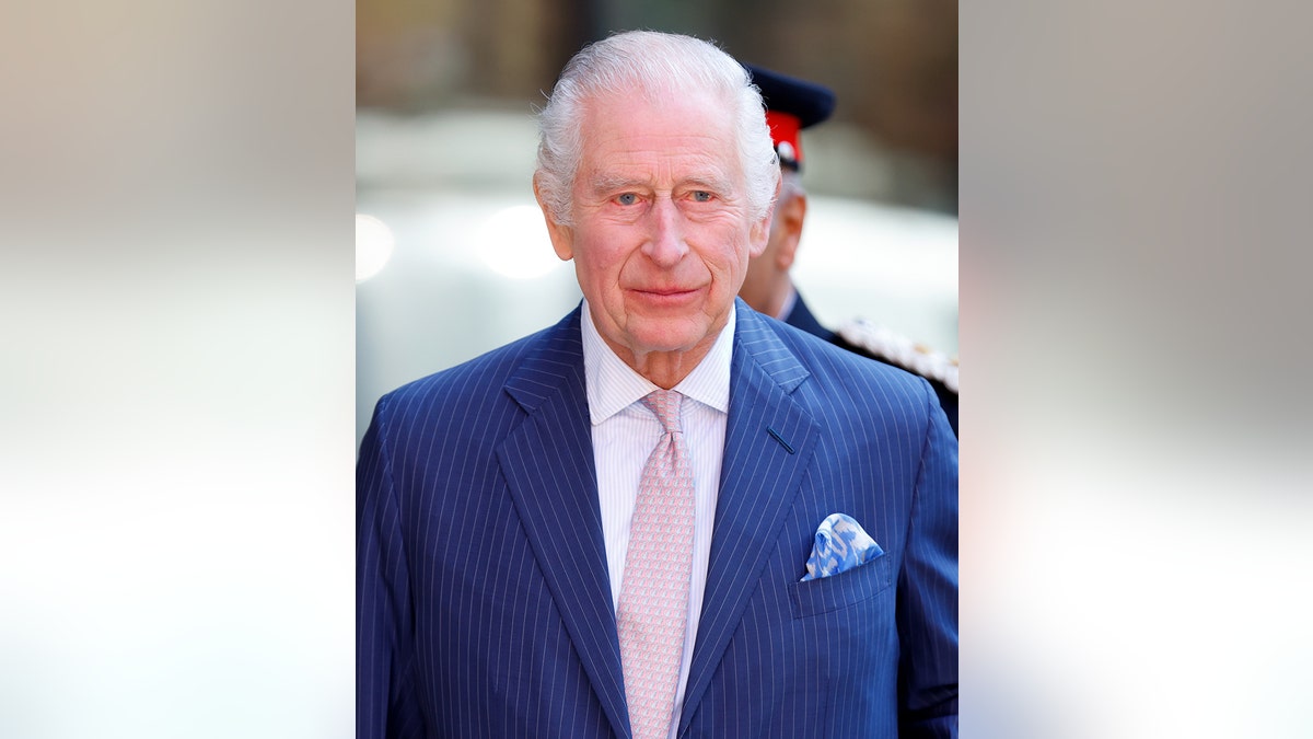 King Charles wearing a blue suit and a dinosaur-printed tie.