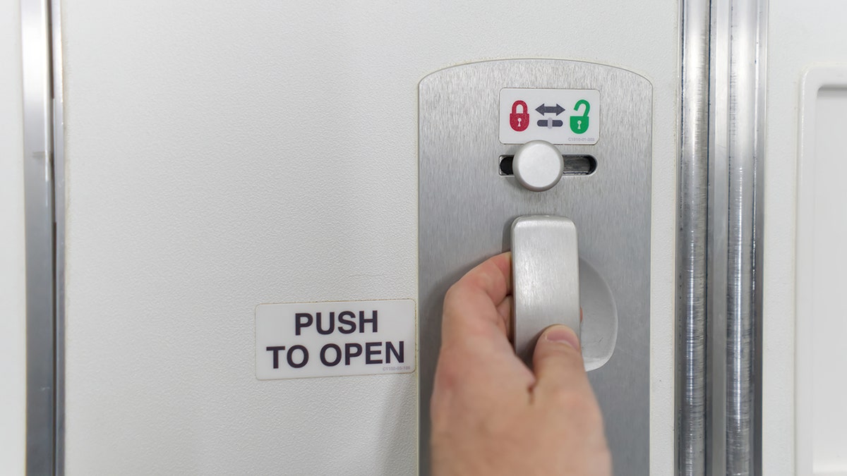 People grab the door handle in the bathroom of an airplane