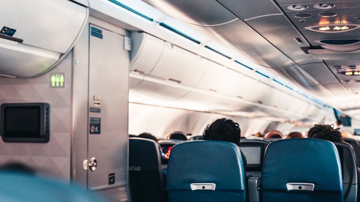 airplane passengers are seated next to the bathroom