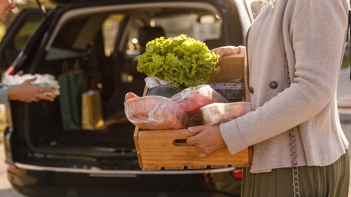 Woman unloading groceries from trunk