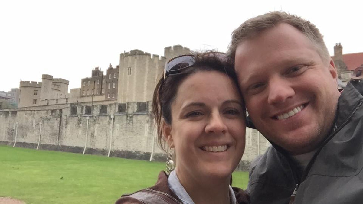 Angela and James Craig pose for selfie with green lawn and gray castle in background