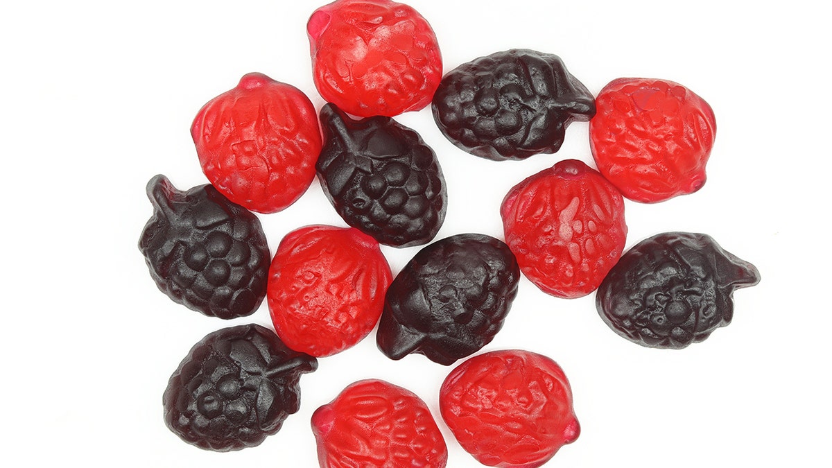 Black and red berry-shaped fruit snacks are shown on a white background.